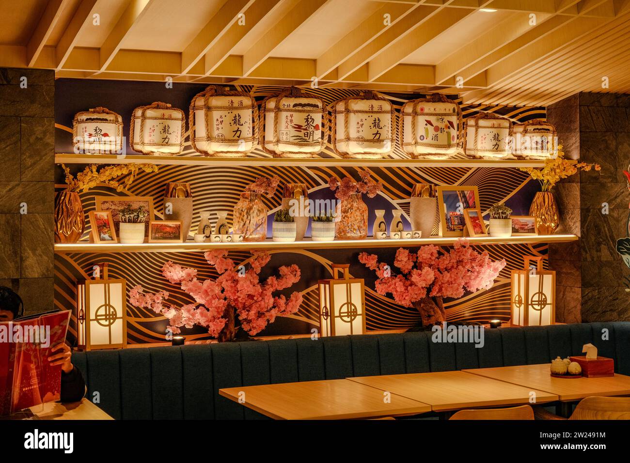 Genießen Sie das gemütliche Ambiente eines japanischen Restaurants mit Blumen und Laternen an den Wänden. Die intime Umgebung fängt das Wesen Japans ein Stockfoto