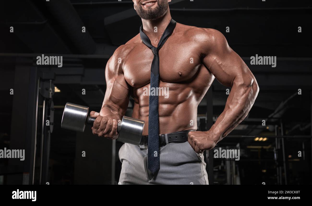 Ein attraktiver Mann mit Krawatte arbeitet im Fitnessstudio. Business- und Bodybuilding-Konzept. Sportliche Aktivitäten. Gemischte Medien Stockfoto