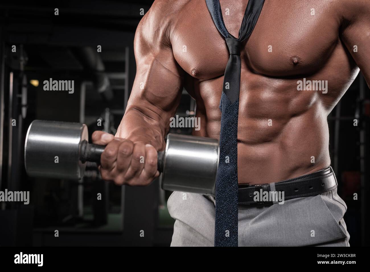 Ein attraktiver Mann mit Krawatte arbeitet im Fitnessstudio. Business- und Bodybuilding-Konzept. Sportliche Aktivitäten. Gemischte Medien Stockfoto