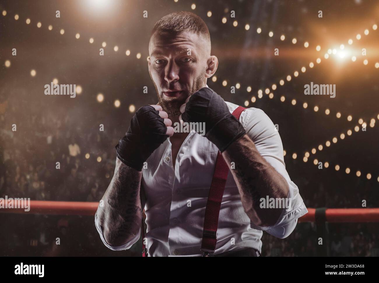 Brutal man Fighter steht im Ring vor dem Hintergrund der Arena und im Scheinwerferlicht. Er sieht bedrohlich in die Kamera. Das Konzept der Faust Stockfoto