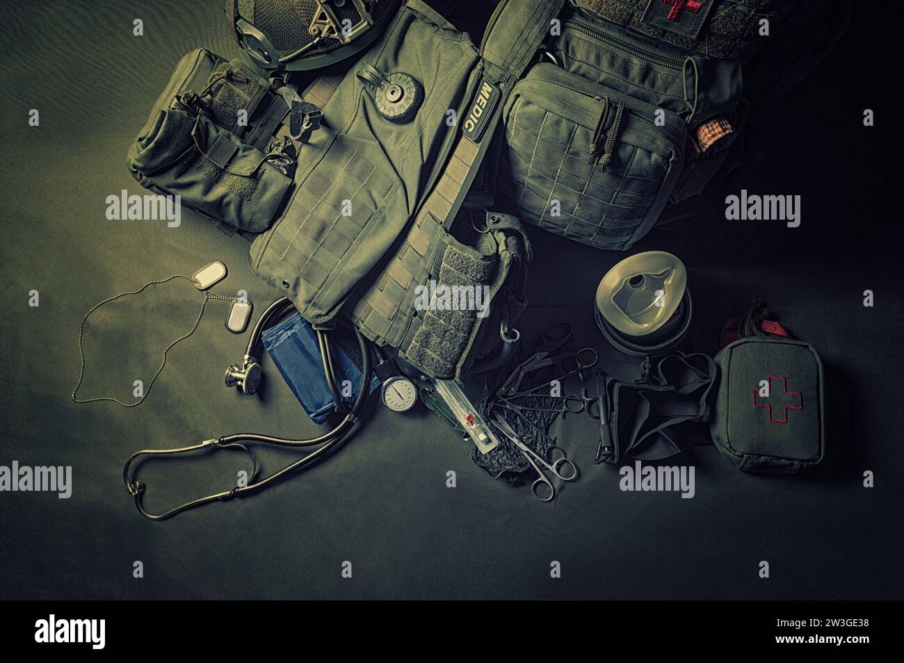 Der Rucksack eines Militärmediziners steht auf grünem Hintergrund. In der Nähe befinden sich ein erste-Hilfe-Kasten und verschiedene Arztwerkzeuge. Blick von oben. Gemischte Medien Stockfoto