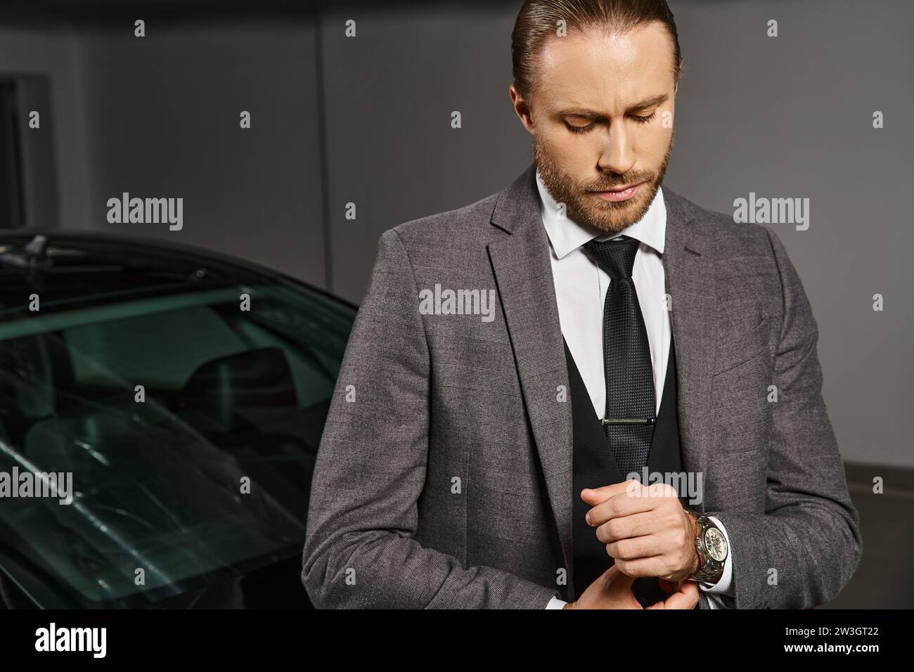 Hübscher rothaariger Geschäftsmann in elegantem Anzug mit Krawatte und Armbanduhr, der neben seinem Auto posiert Stockfoto