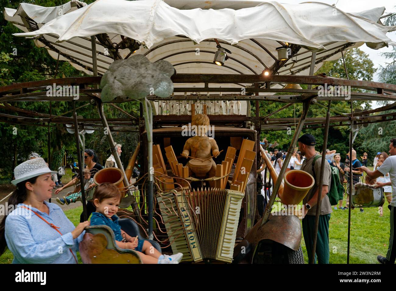Malerisches, handbetriebenes Karussell während des Schweizer Tages, bei dem Eltern ihre Kinder auf Schaukelstühlen um einen hölzernen Trommeljungen schieben. Stockfoto