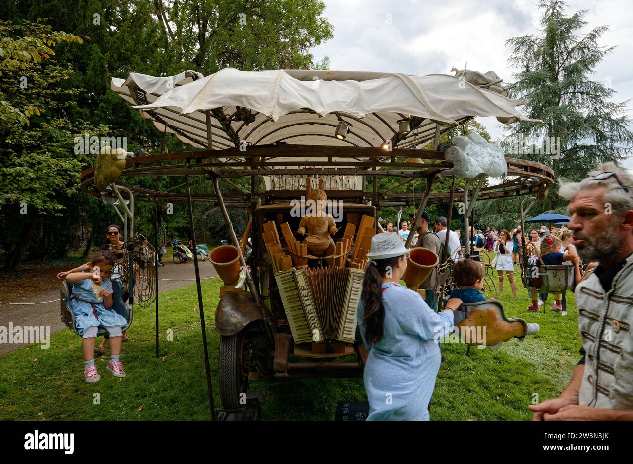 Malerisches, handbetriebenes Karussell während des Schweizer Tages, bei dem Eltern ihre Kinder auf Schaukelstühlen um einen hölzernen Trommeljungen schieben. Stockfoto