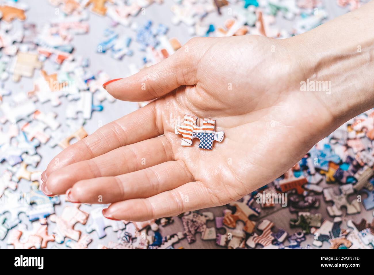 Die Frau hält Puzzle mit der us-Flagge. Wirtschaftliches und politisches Konzept. Gemischte Medien Stockfoto