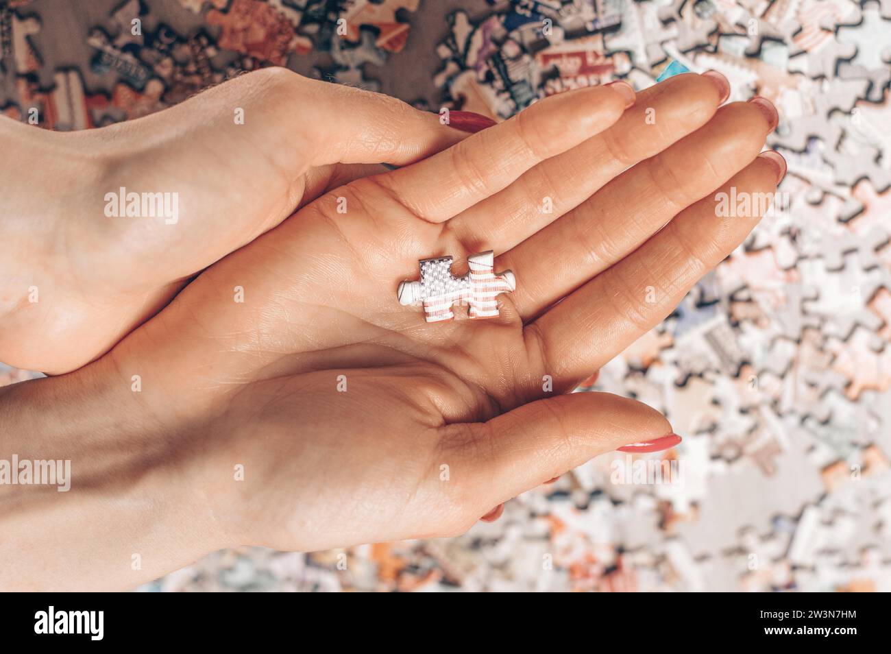 Die Frau hält Puzzle mit der us-Flagge. Wirtschaftliches und politisches Konzept. Gemischte Medien Stockfoto