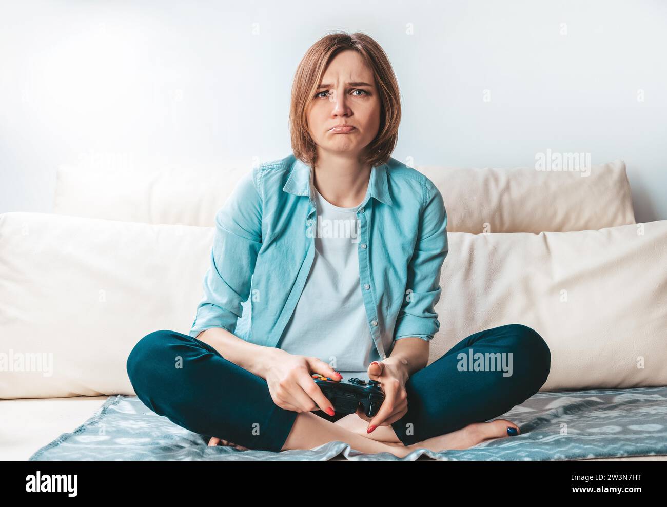 Ein Mädchen mit einem Joystick in der Hand weint wegen einer Niederlage im Spiel. ESports-Konzept. Gemischte Medien Stockfoto