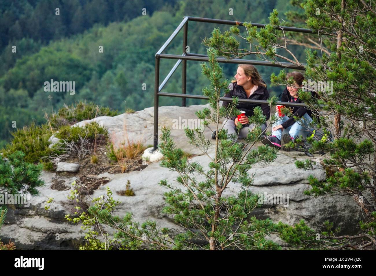 Zwei Mädchen sitzen auf einer Spitze des Elbsandsteingebirges und blicken auf die Landschaft, Sachsen Deutschland Europa Stockfoto