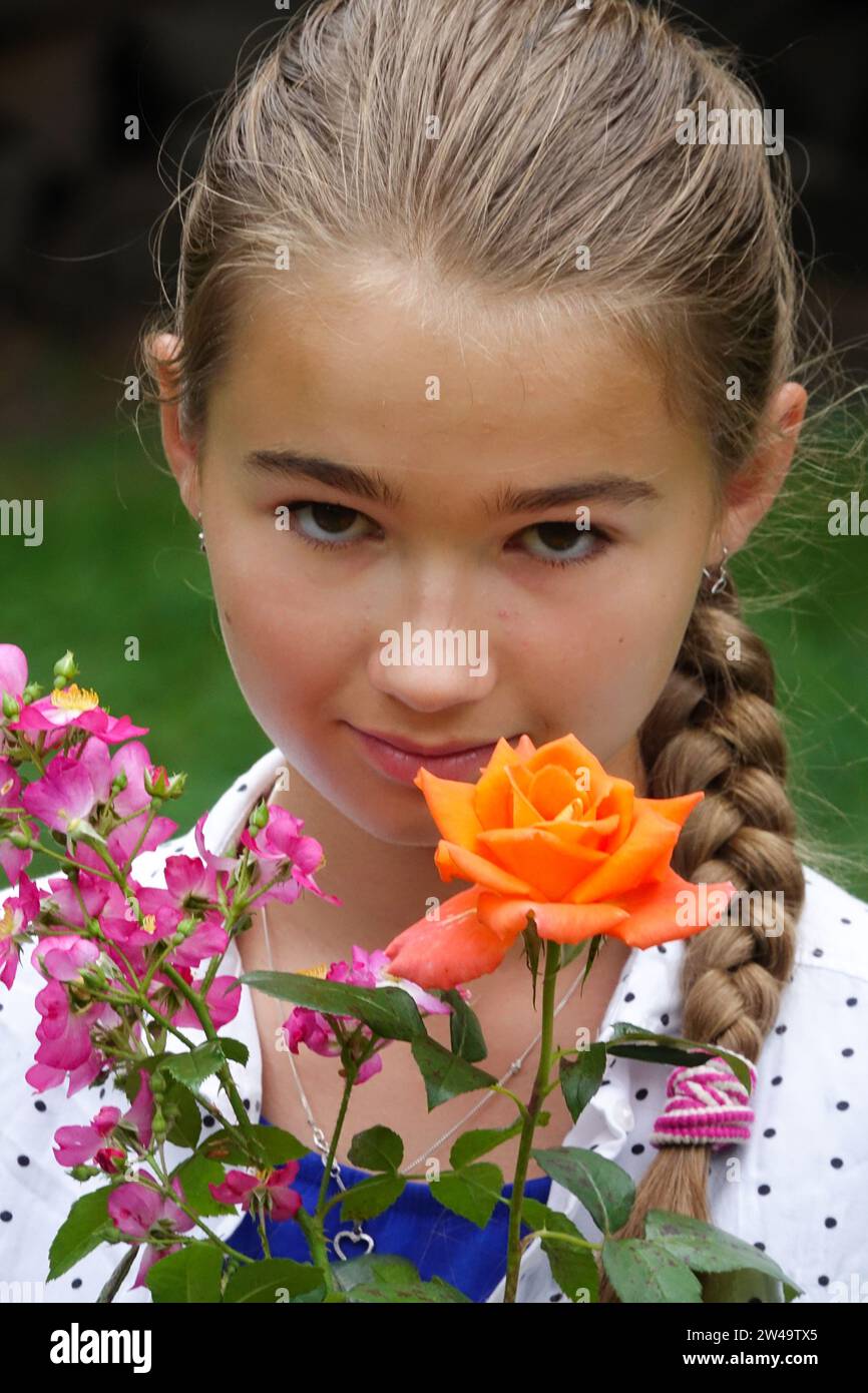 Teenager-Mädchen, das durch einen Blumenstrauß in die Kamera schaut Stockfoto