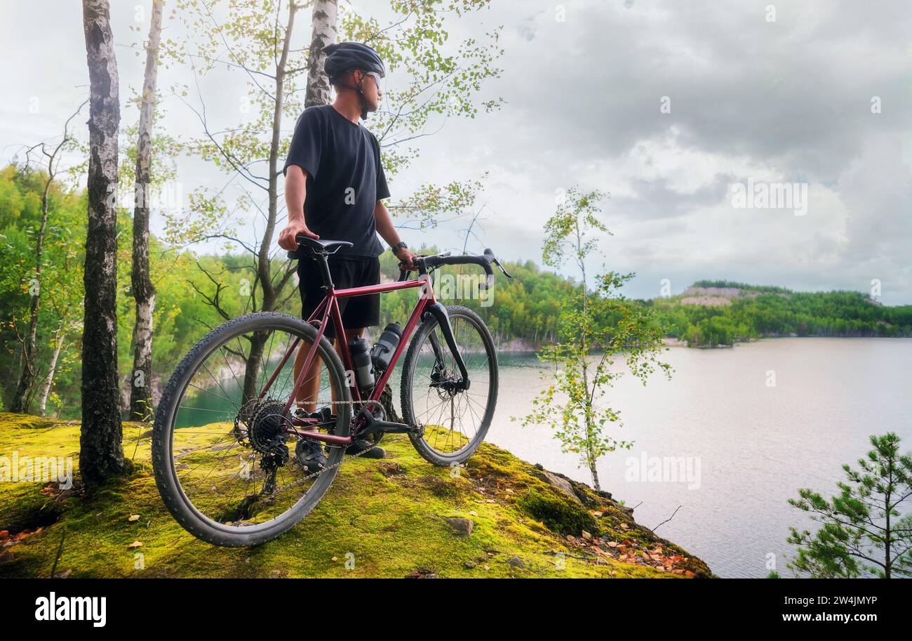 Junger aktiver Mann mit Helm steht mit einem Fahrrad am Rand einer Klippe. Sport und Reisen. Stockfoto