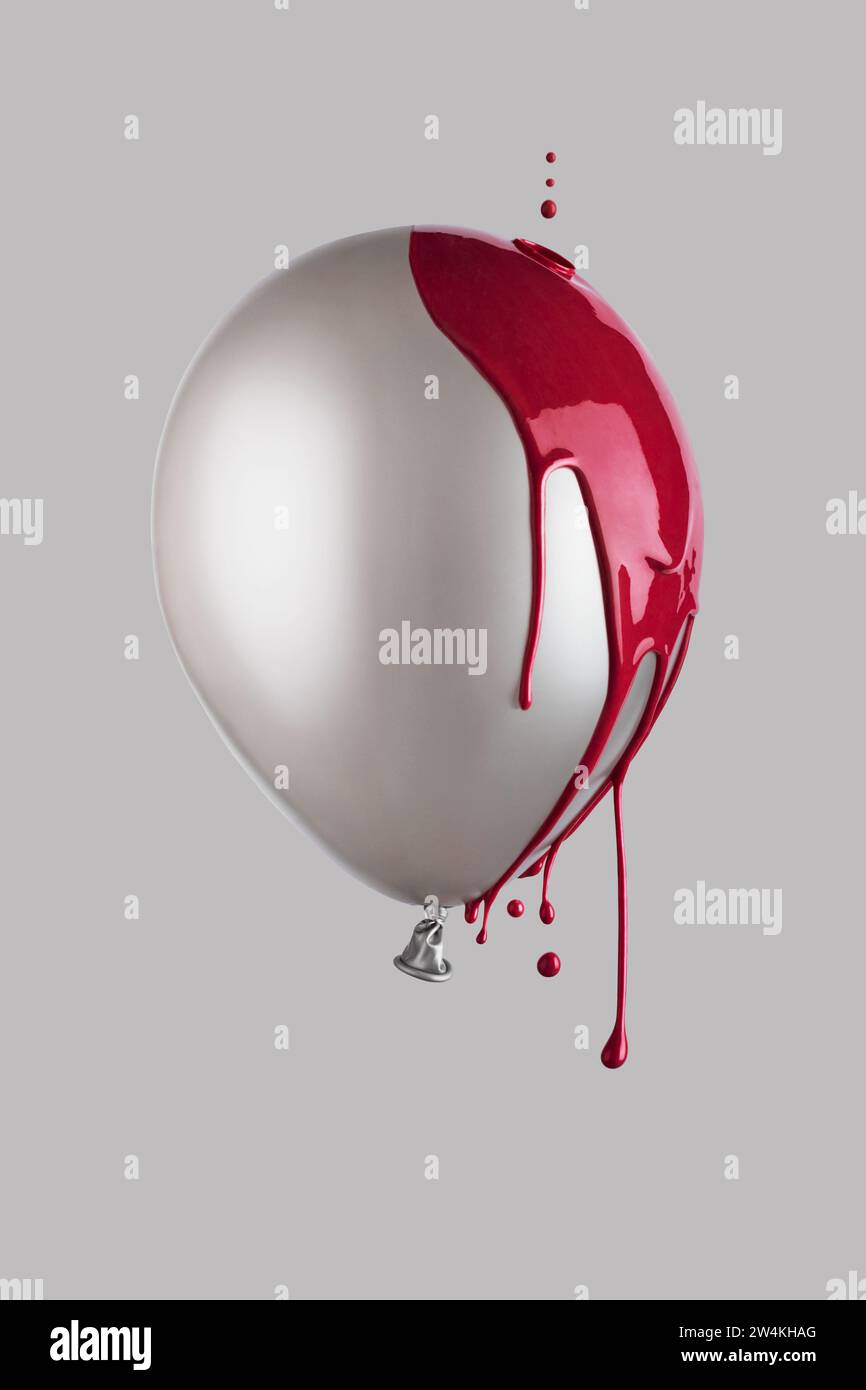 Rote Farbe tropft auf einen grauen Ballon, der in der Luft schwimmt. Minimalistisches trendiges Konzept. Stockfoto