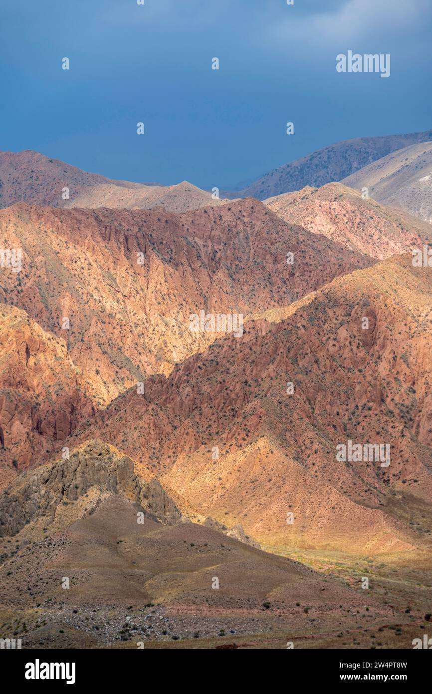 Rote und orangene Berge in stimmungsvollem Licht, dramatischer bewölkter Himmel, Berglandschaft in der Nähe von Kasarman, Naryn Region, Kirgisistan Stockfoto