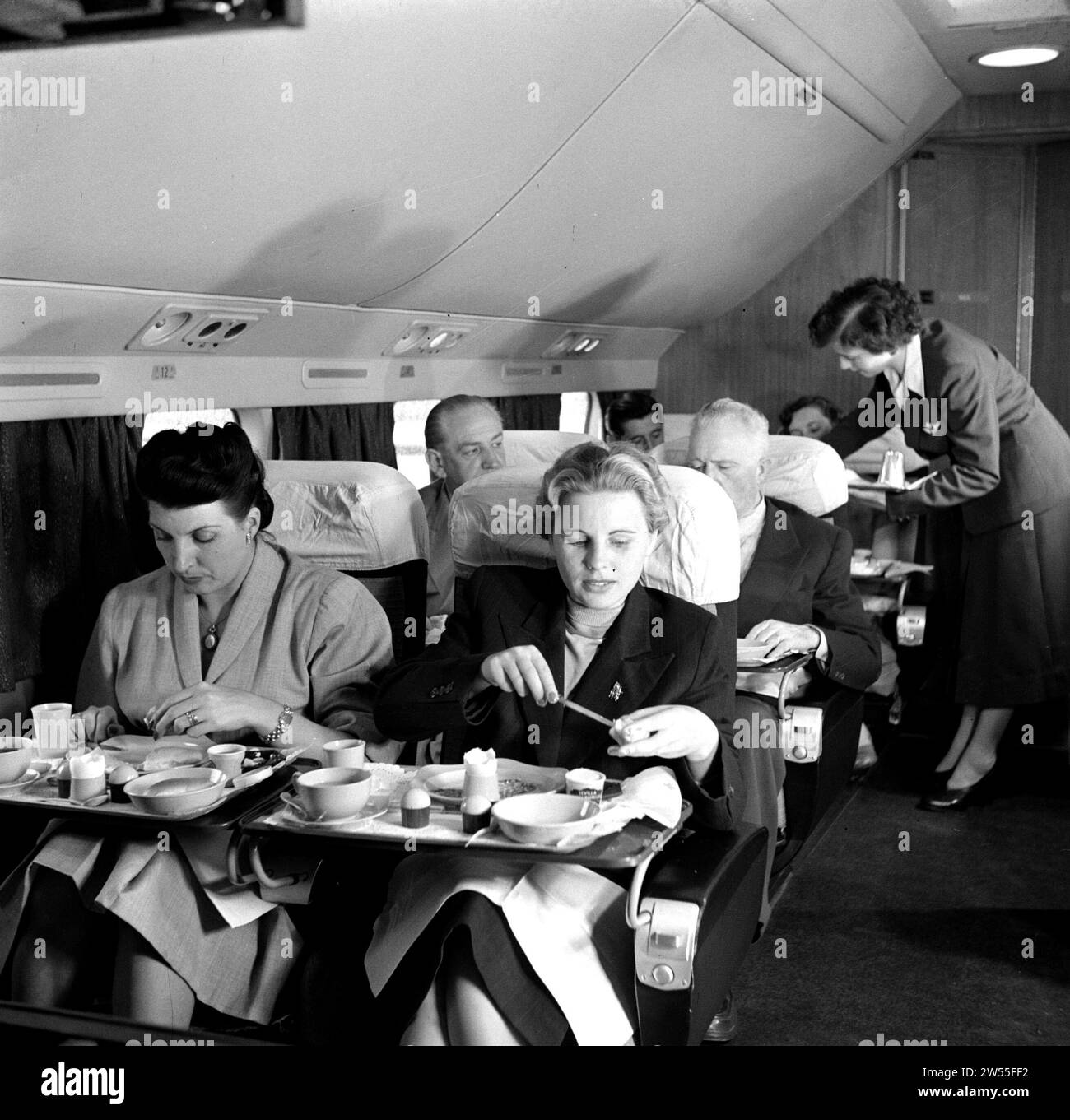 Ein KLM-Flugbegleiter serviert eine Mahlzeit an Bord eines KLM-Passagierflugzeugs CA. 1950 Stockfoto