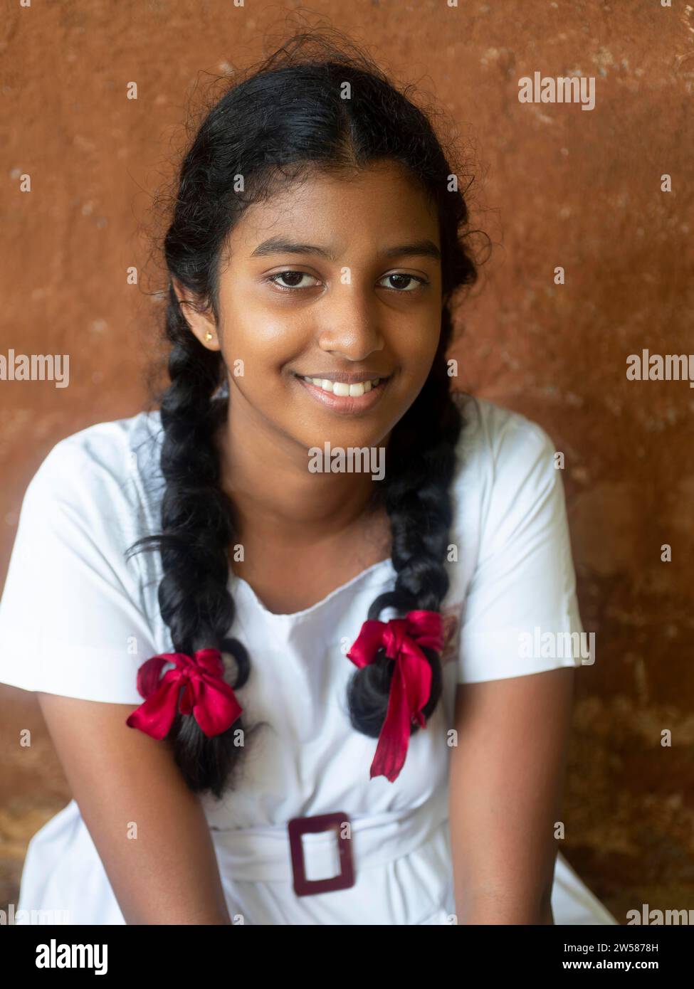 Singhalesisches Schulmädchen mit weißer Kleidung, schwarzen Zöpfen und roten Bändern, Sri Lanka Stockfoto