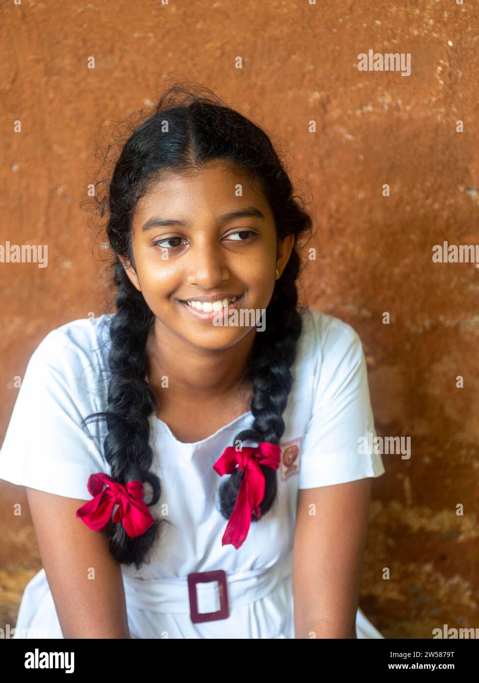 Singhalesisches Schulmädchen mit weißer Kleidung, schwarzen Zöpfen und roten Bändern, Sri Lanka Stockfoto