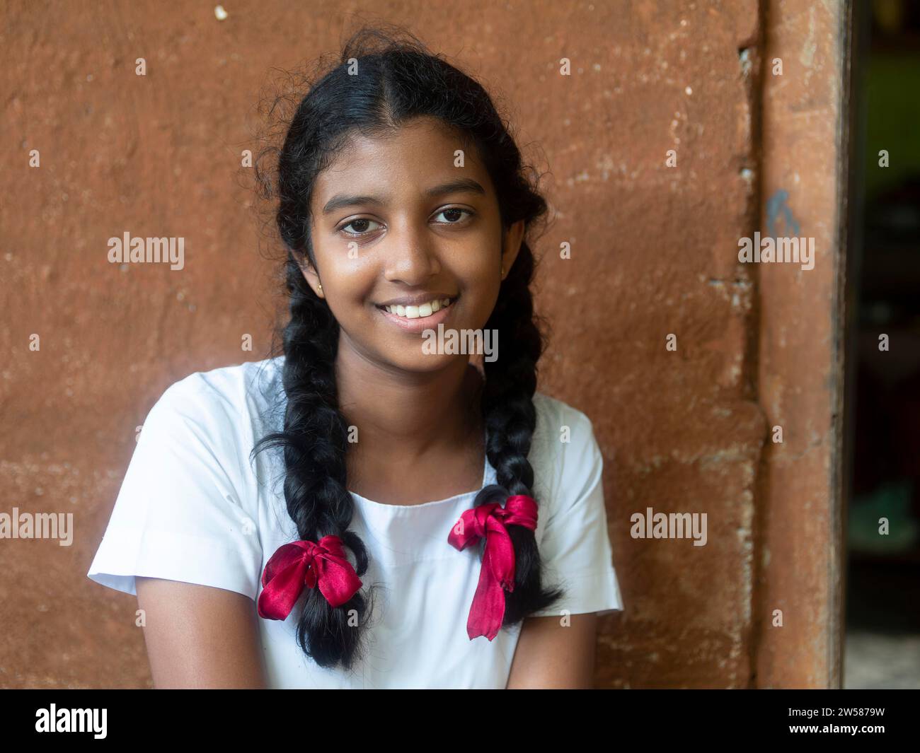Singhalesisches Schulmädchen mit weißer Kleidung, schwarzen Zöpfen und roten Bändern, Sri Lanka Stockfoto