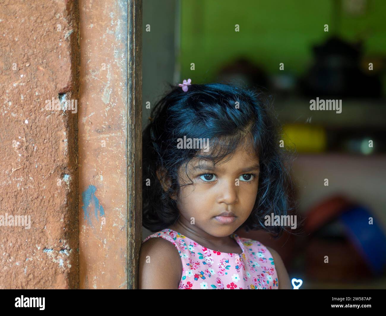 Ein kleines singhalesisches Mädchen mit großen Augen und schwarzen Haaren steht vor der Tür, Sri Lanka Stockfoto
