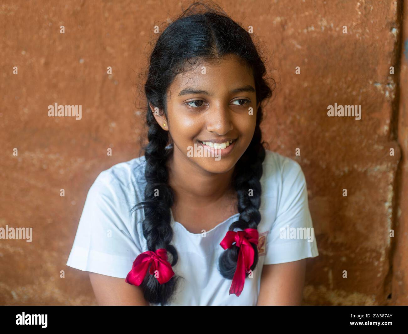 Singhalesisches Schulmädchen mit weißer Kleidung, schwarzen Zöpfen und roten Bändern, Sri Lanka Stockfoto