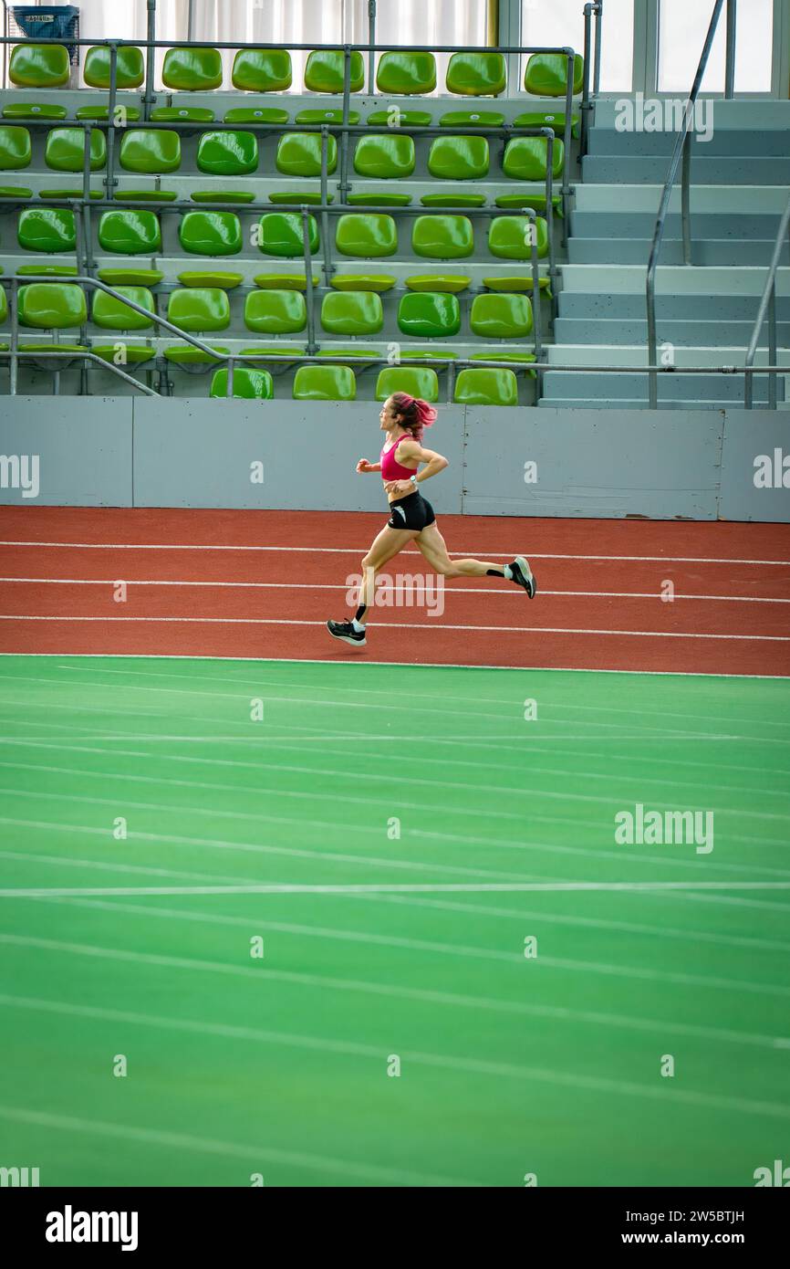 Einziger Läufer in einem leeren, großen Stadion, Laufbahn und grünen Sitzen, Glaspalast, Sindelfingen Stockfoto