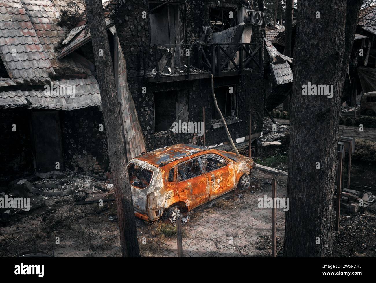 Verbranntes Auto und zerstörtes Gebäude. Die Folgen der Mörtelbeschussung. Krieg in der Ukraine. Kiew Region, Irpin Stadt, 2022. Stockfoto