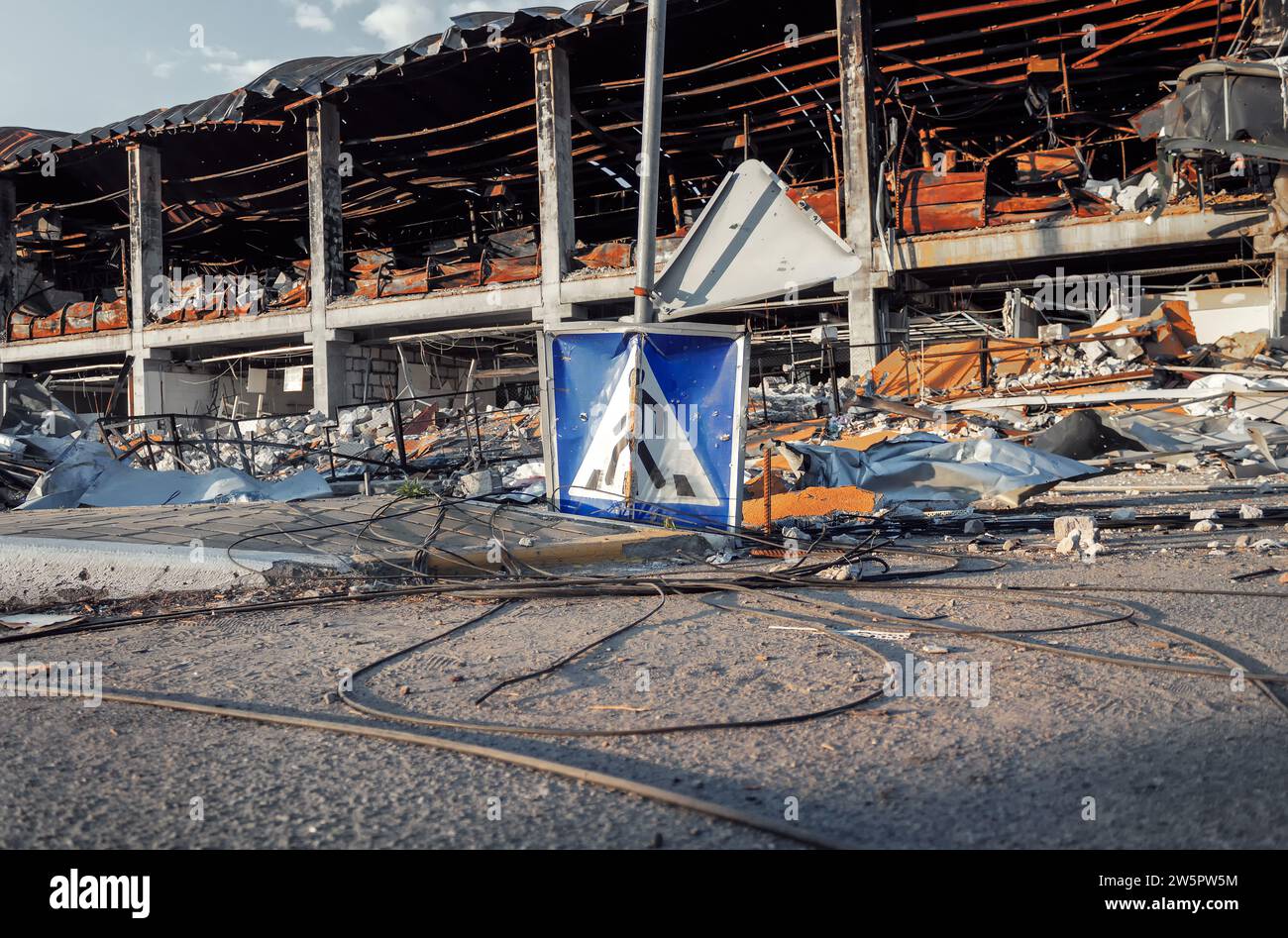 Fußgängerschild auf dem Hintergrund des ruinierten Einkaufszentrums. Die Infrastruktur der Stadt wurde durch Mörserbeschuss zerstört. Irpin, 2022. Krieg in der Ukraine. Stockfoto