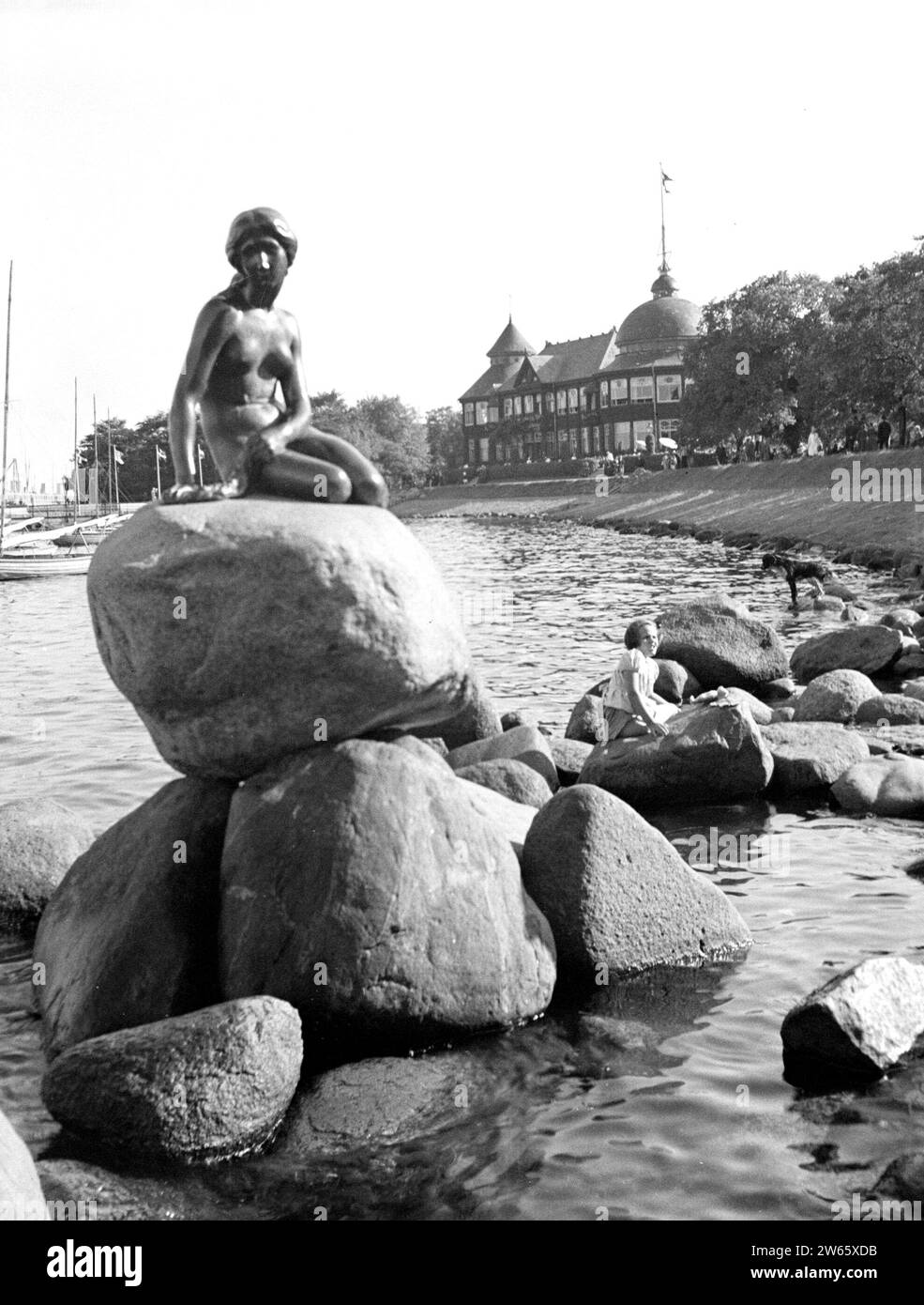 Statue der Kleinen Meerjungfrau auf der Langelinie mit dem jetzt abgerissenen Langelinie Pavillon im Hintergrund ca. 1934 Stockfoto