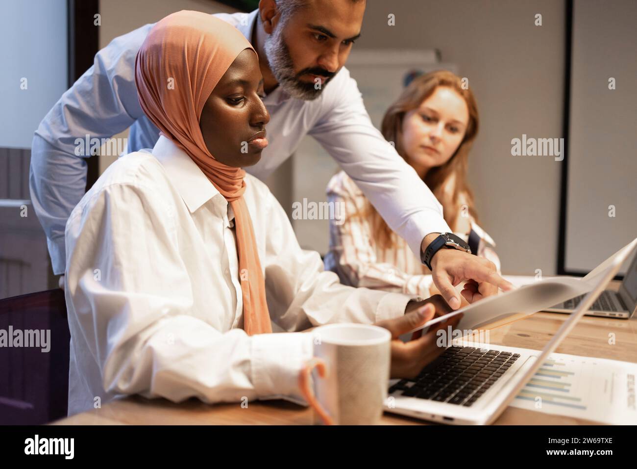 Konzentrierte sich auf verschiedene Kollegen mit Laptop und Dokumenten, die neue Geschäftsstrategie diskutierten, während sie in modernen Büros an Projekten arbeiteten Stockfoto