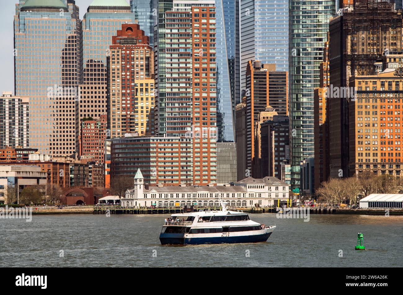 Eine Nahaufnahme der architektonischen Vielfalt Manhattans mit einer Mischung aus alten Backsteinstrukturen und modernen Glashochhäusern. In der Hu wird eine Fähre gesehen Stockfoto