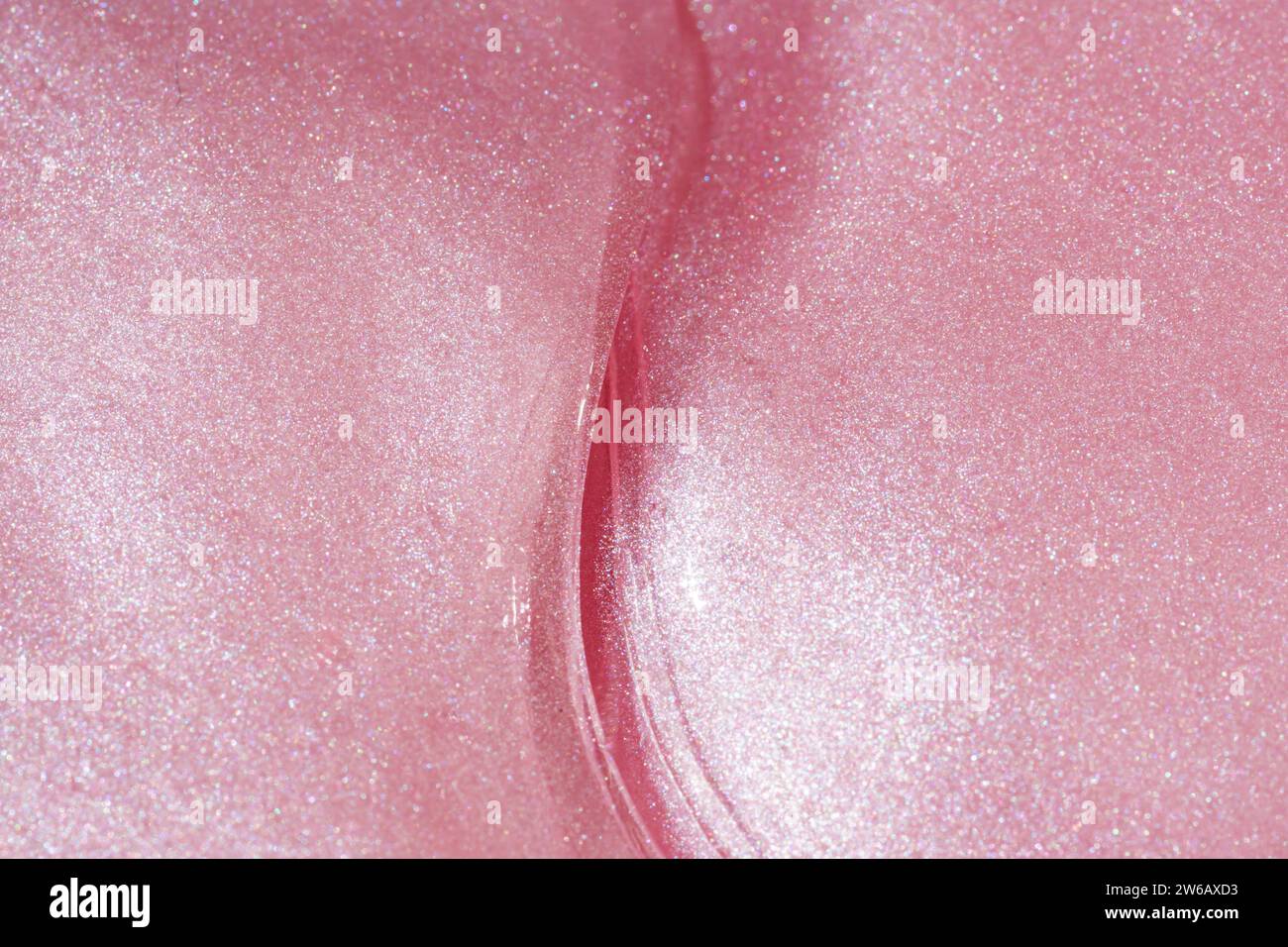 Dies ist ein Nahaufnahme-Bild, das die Details einer schimmernden rosafarbenen Oberfläche mit einer anmutigen Kurve zeigt, die ein abstraktes Design schafft. Stockfoto