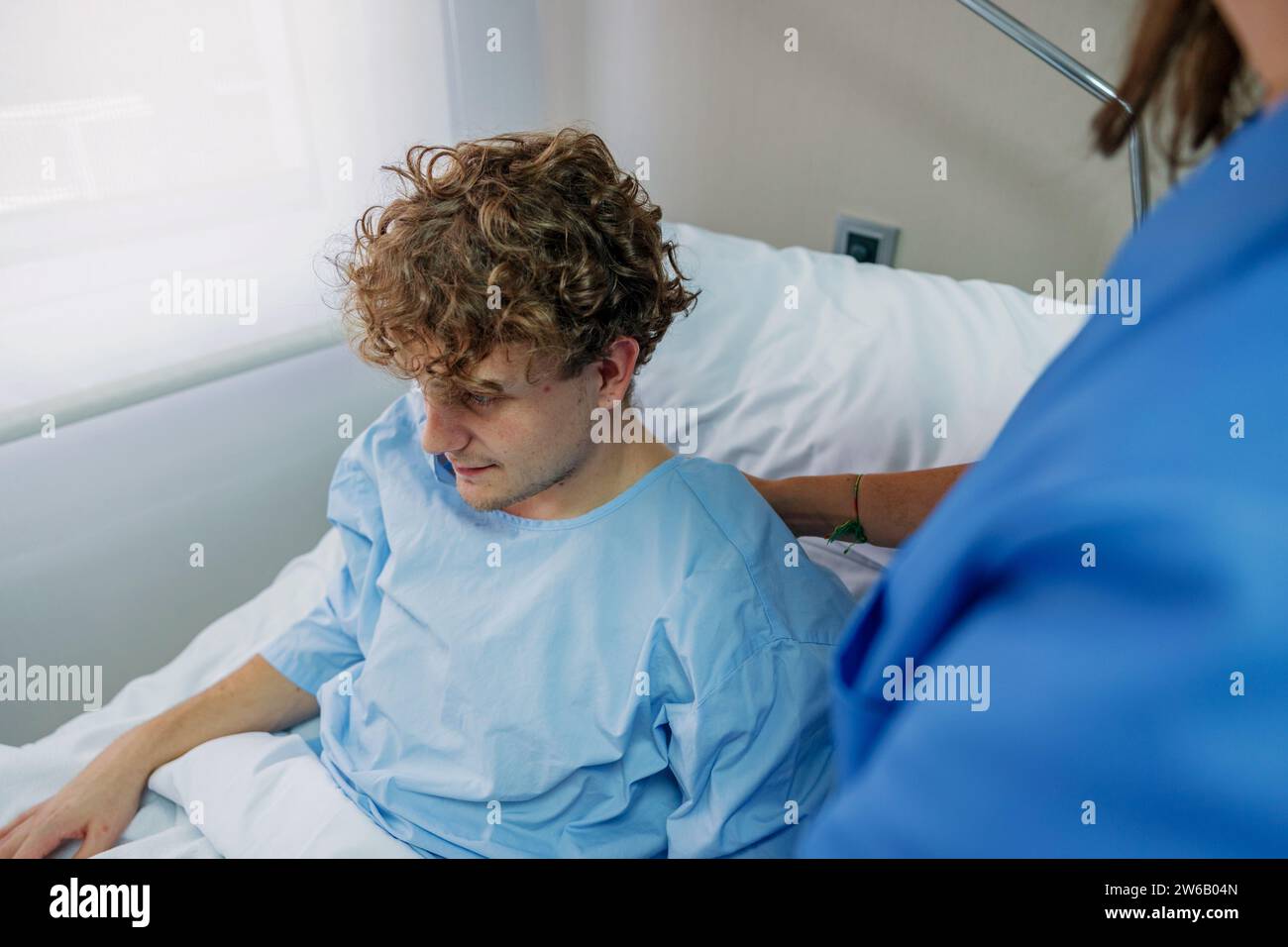 Von oben über der Ernte weibliche Ärztin überprüft Patienten sitzend auf Bett im Krankenhaus während der Arbeit in der Klinik Stockfoto