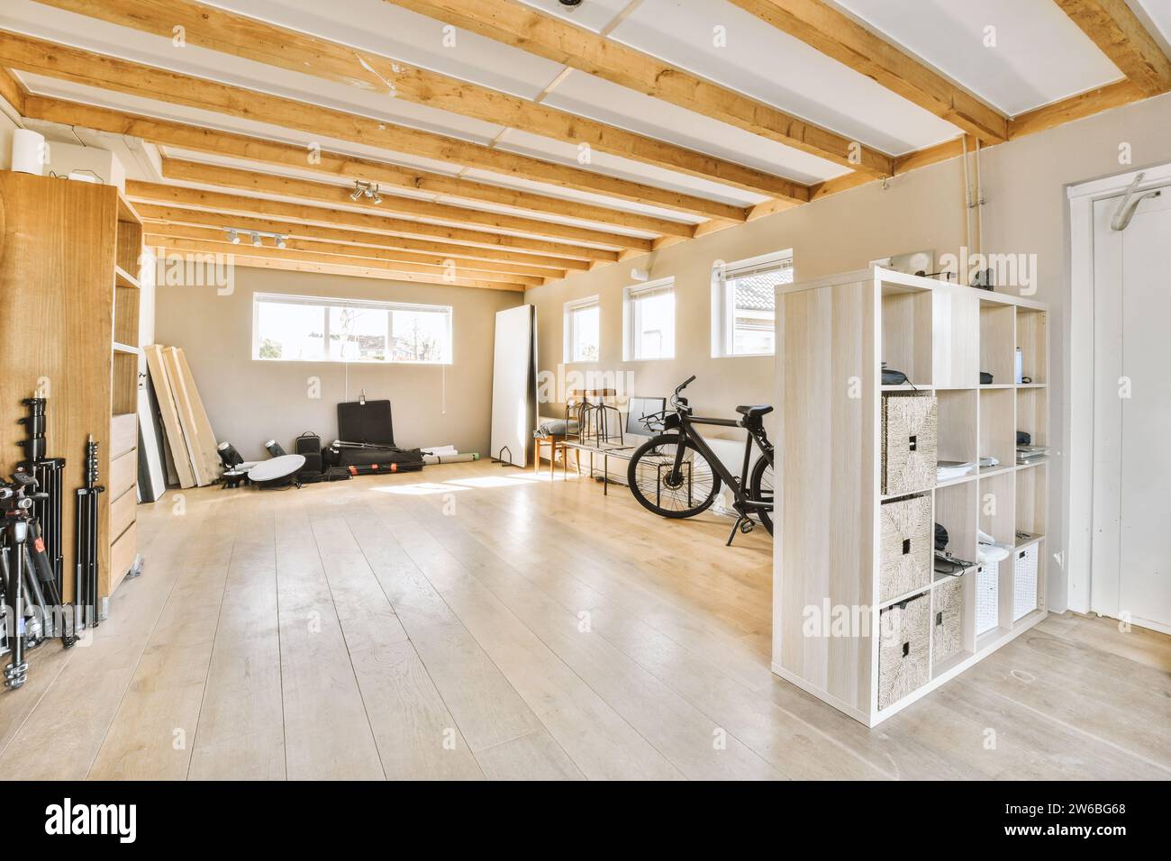 Das Innere der geräumigen Garage mit Fahrrad und Holzregalen und verschiedenen Sachen in einem modernen Haus mit weißen Wänden und Holzbalken Stockfoto