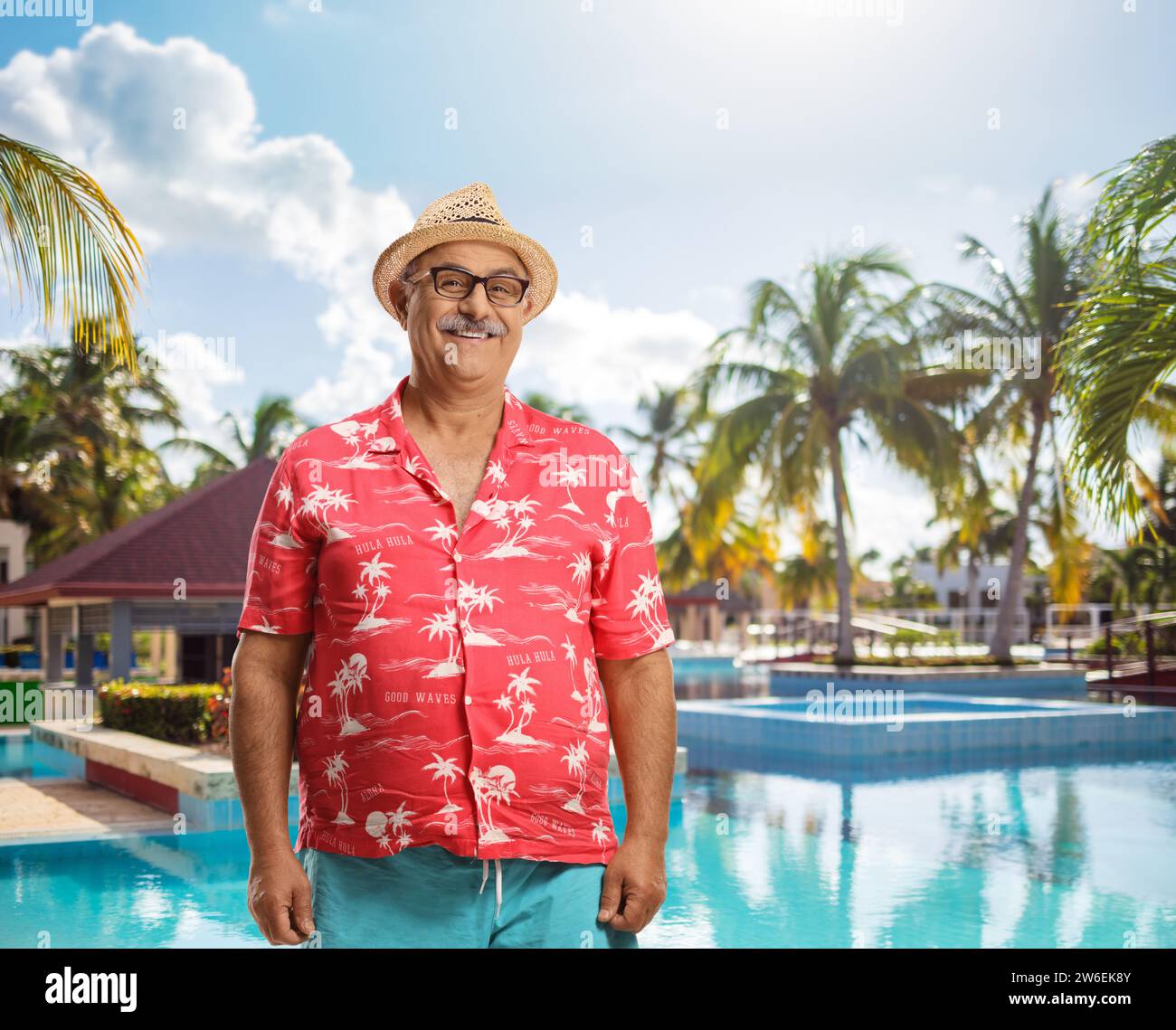 Reifer männlicher Tourist lächelt vor einem Außenpool in die Kamera Stockfoto