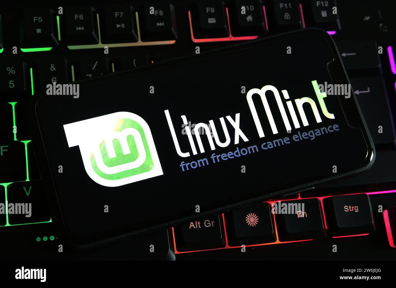 Viersen, Deutschland - 9. Dezember. 2023: Großaufnahme des Smartphones auf Computertastatur mit Logo-Schriftzug von linux Mint Stockfoto