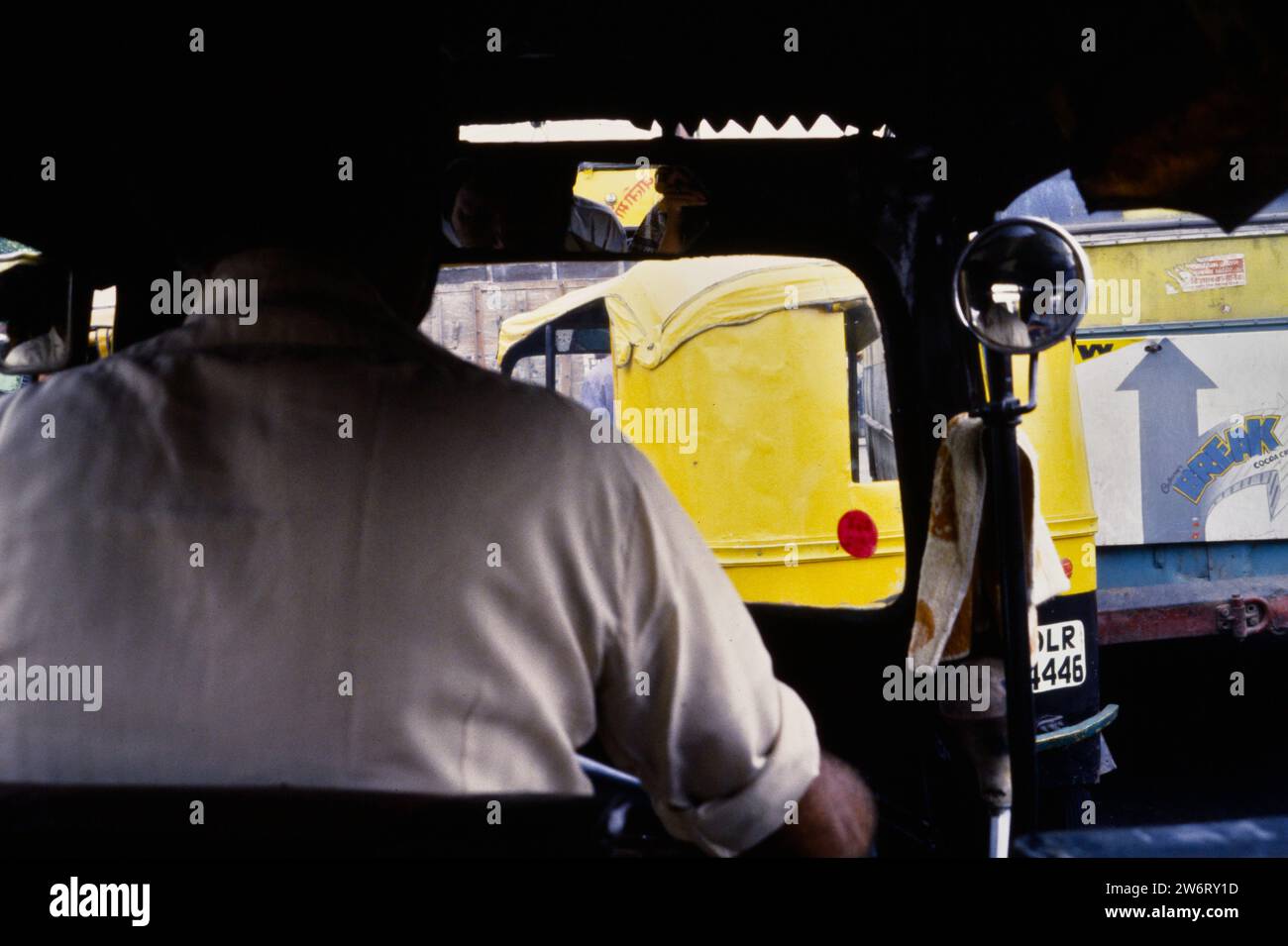 Archiv Historisches Bild von der Rückseite Einer Tuk Tuk Auto Rikscha mit Blick auf die Rückseite des Rikscha Wallah Driver durch die Frontscheibe des Conjested Traffic Ahead, Delhi, Indien 1990 Stockfoto