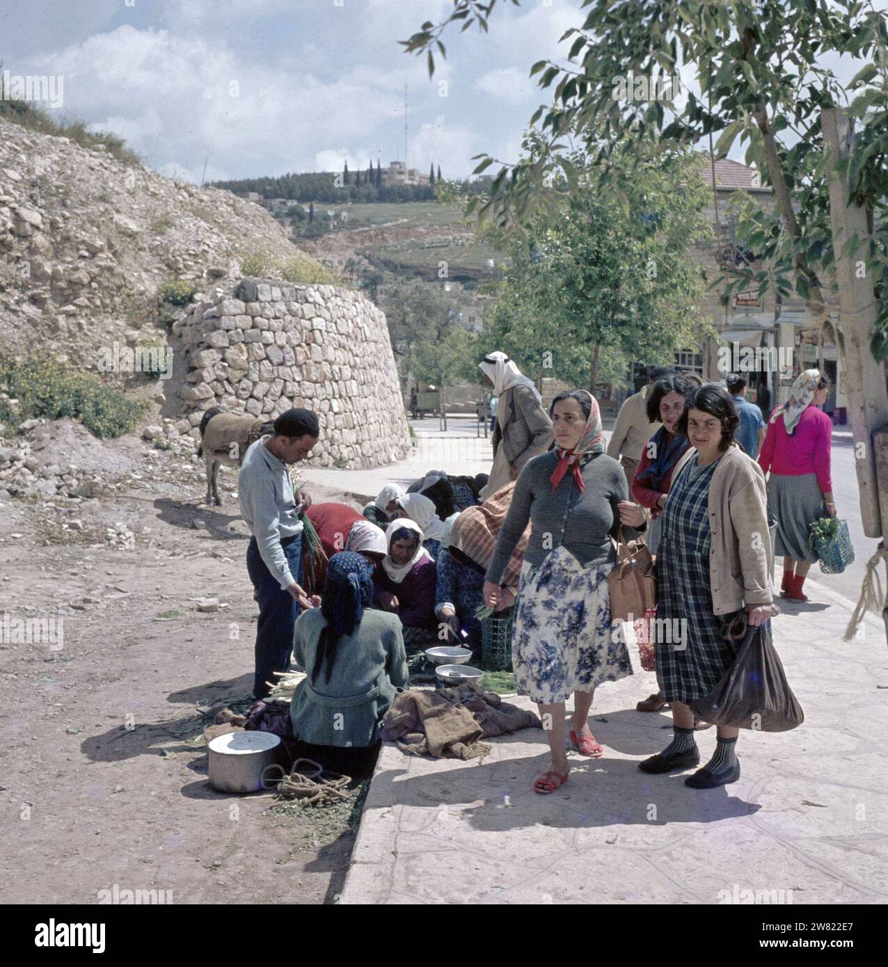 Sicher. Frauen verkaufen Gemüse auf einem Platz. Auf dem Boden Gemüse, Jutebeutel und eine Waage mit einem Gewicht von ca. 1960er Jahre Stockfoto