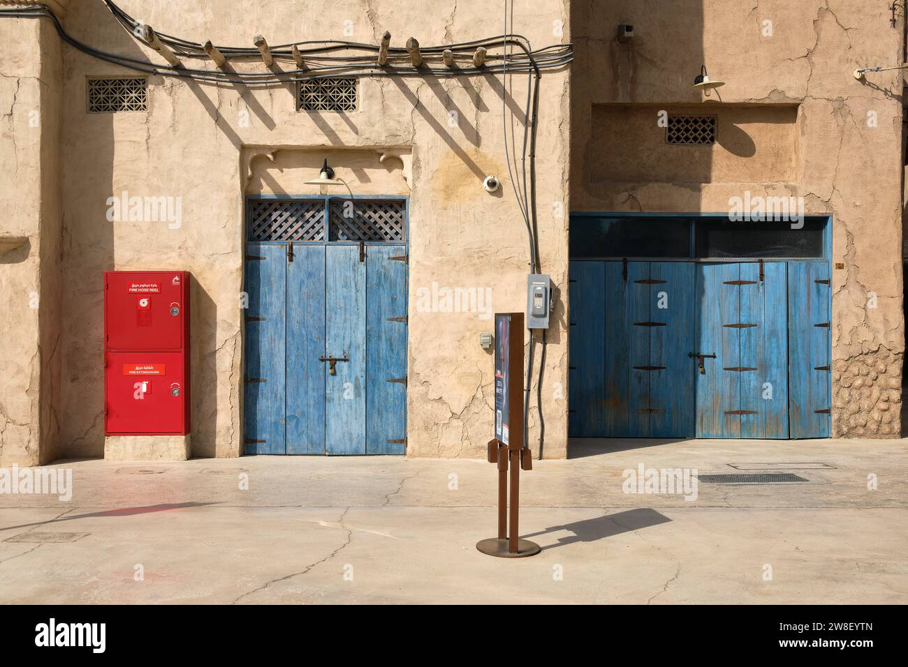 Roter Brandschutz neben blauen verwitterten Türen im historischen Viertel Al Fahidi, Dubai, Vereinigte Arabische Emirate Stockfoto