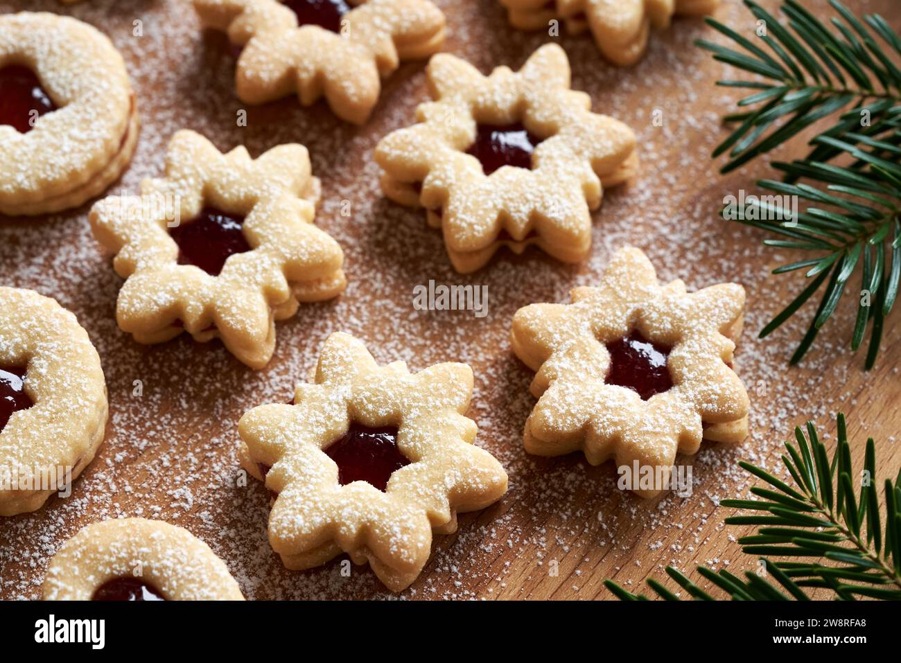 Sternförmige Linzer Weihnachtskekse gefüllt mit Erdbeermarmelade und mit Zucker auf einem Holzbrett bestäubt Stockfoto