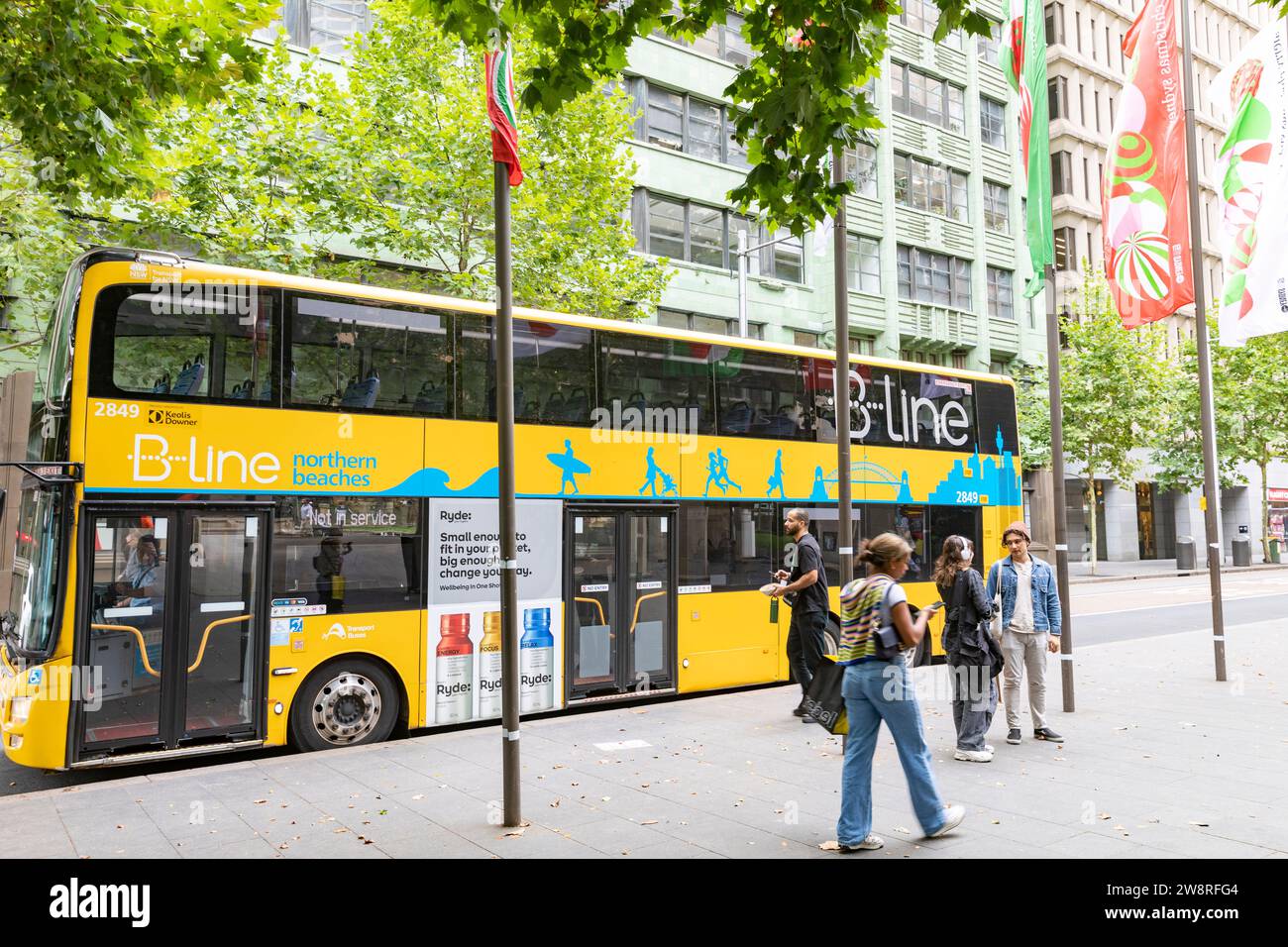 Sydney Australia B Line gelber Doppeldeckerbus an einer Haltestelle in der York Street Sydney, NSW, Australien, mit weihnachtsbannern im Flug Stockfoto