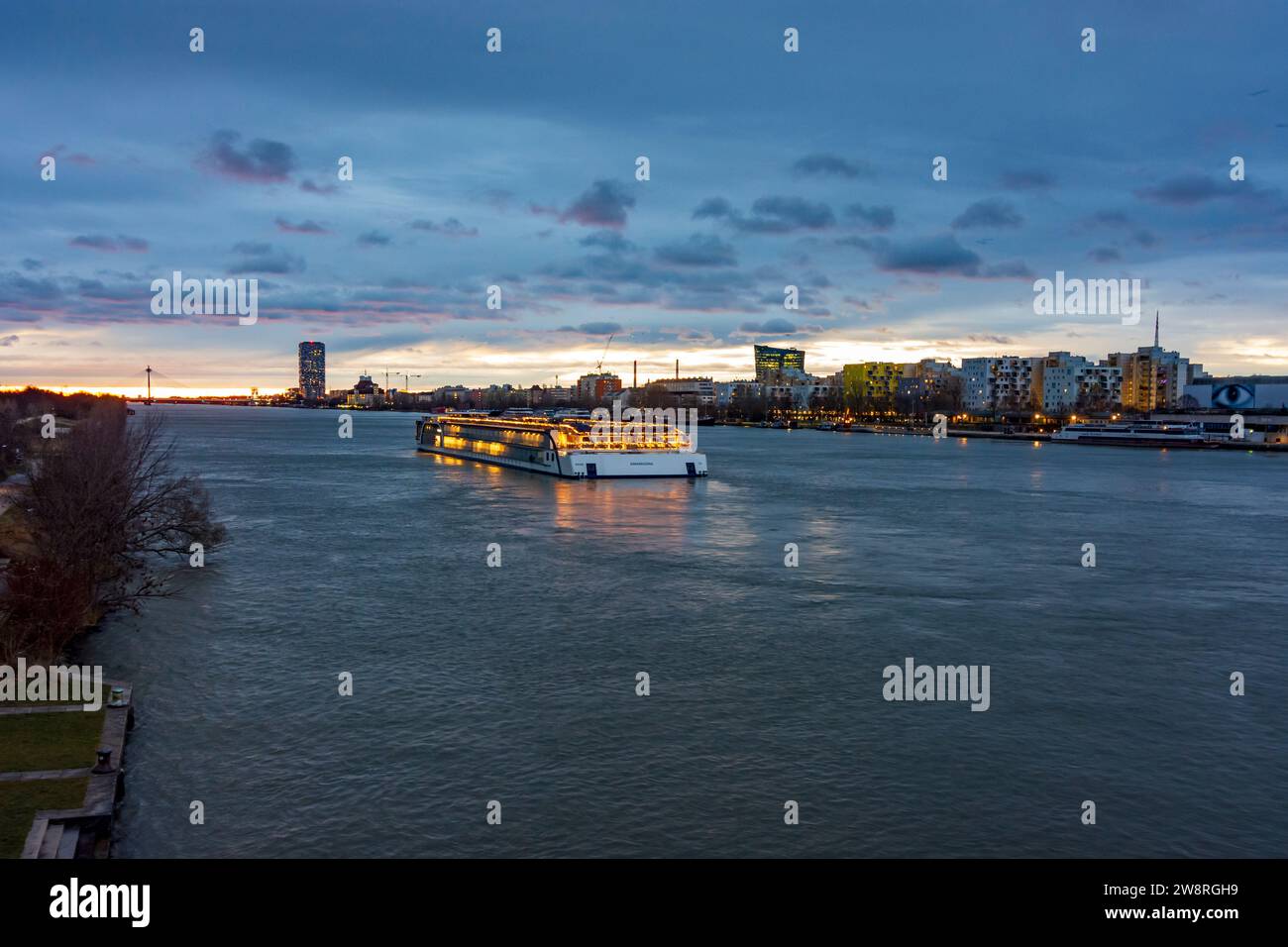 Wien: Sonnenaufgang an der Donau (Donau), Kreuzfahrtschiff in Weihnachtsdekoration, Seilbrücke Donaustadtbrücke, Marina Tower, OMV HaedQuarters in Stockfoto