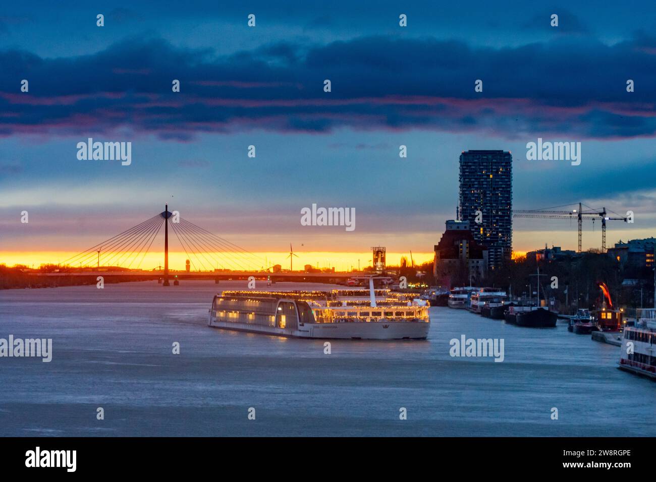 Wien: Sonnenaufgang an der Donau (Donau), Kreuzfahrtschiff in Weihnachtsdekoration, Seilbrücke Donaustadtbrücke, Marina Tower in 02. Leopol Stockfoto