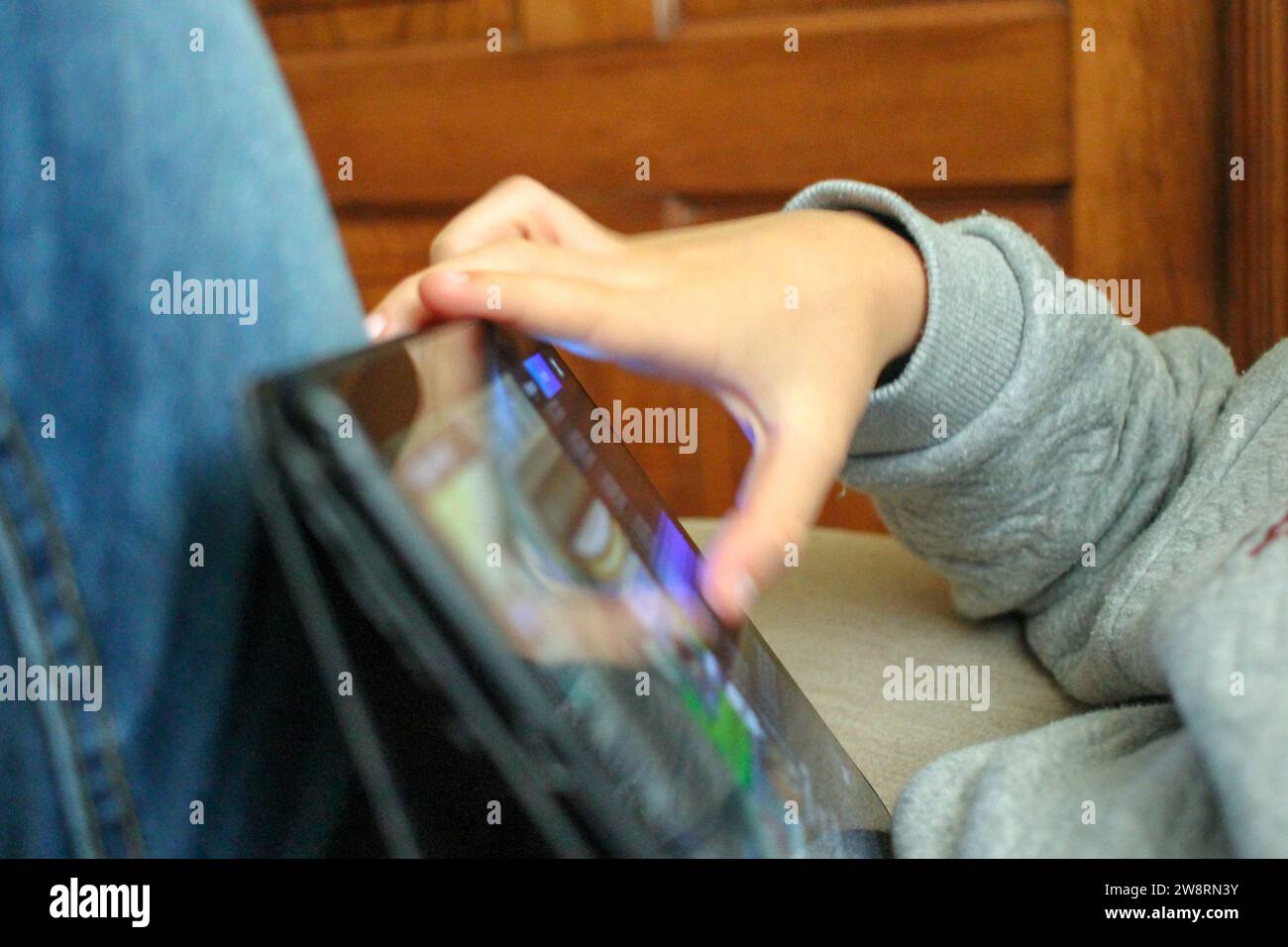 Digitale Tagträume: Das verlorene Kind im Glanz der Tablet-Magie Stockfoto