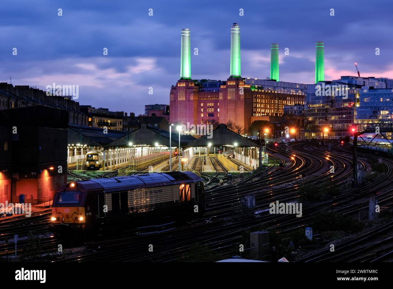 London, Großbritannien. Dezember 2023. Zwei besondere Services - eine Dampfeisenbahn und luxuriöse kulinarische Ausflüge, die von der Londoner Victoria Station in der Vorweihnachtszeit durchgeführt wurden, wo sie an der Battersea Power Station vorbeifuhren, die in der Abenddämmerung in einem festlichen Design des Künstlers David Hockney beleuchtet wurde. Quelle: Eleventh Photography/Alamy Live News Stockfoto