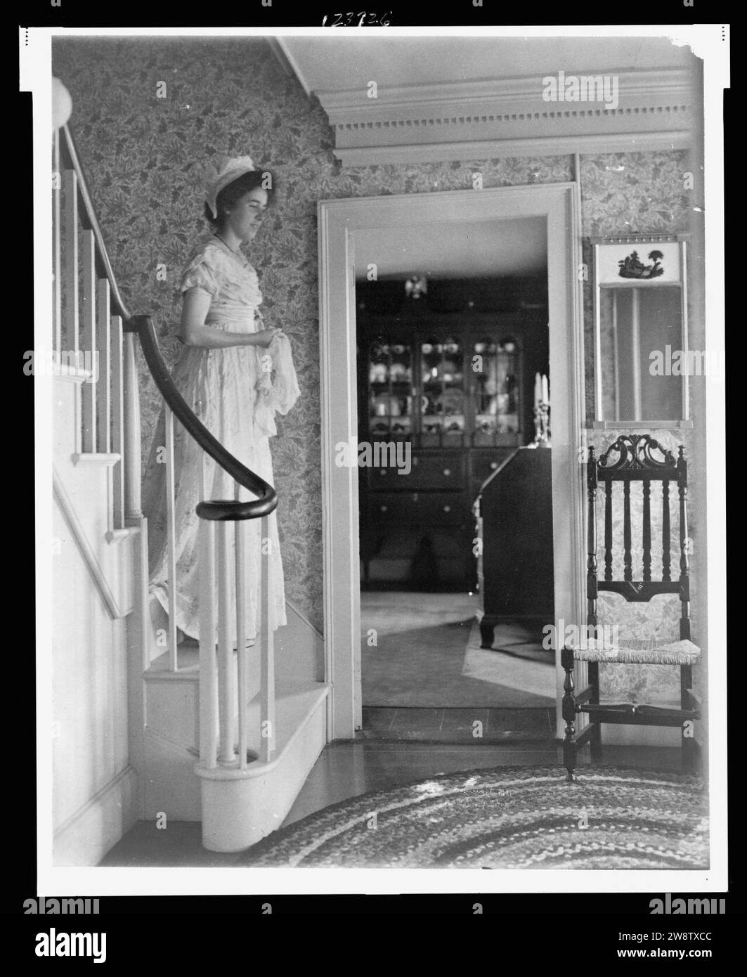 Junge Frau im kolonialen Kleid auf Schritte in Kolonial - American Home Stockfoto