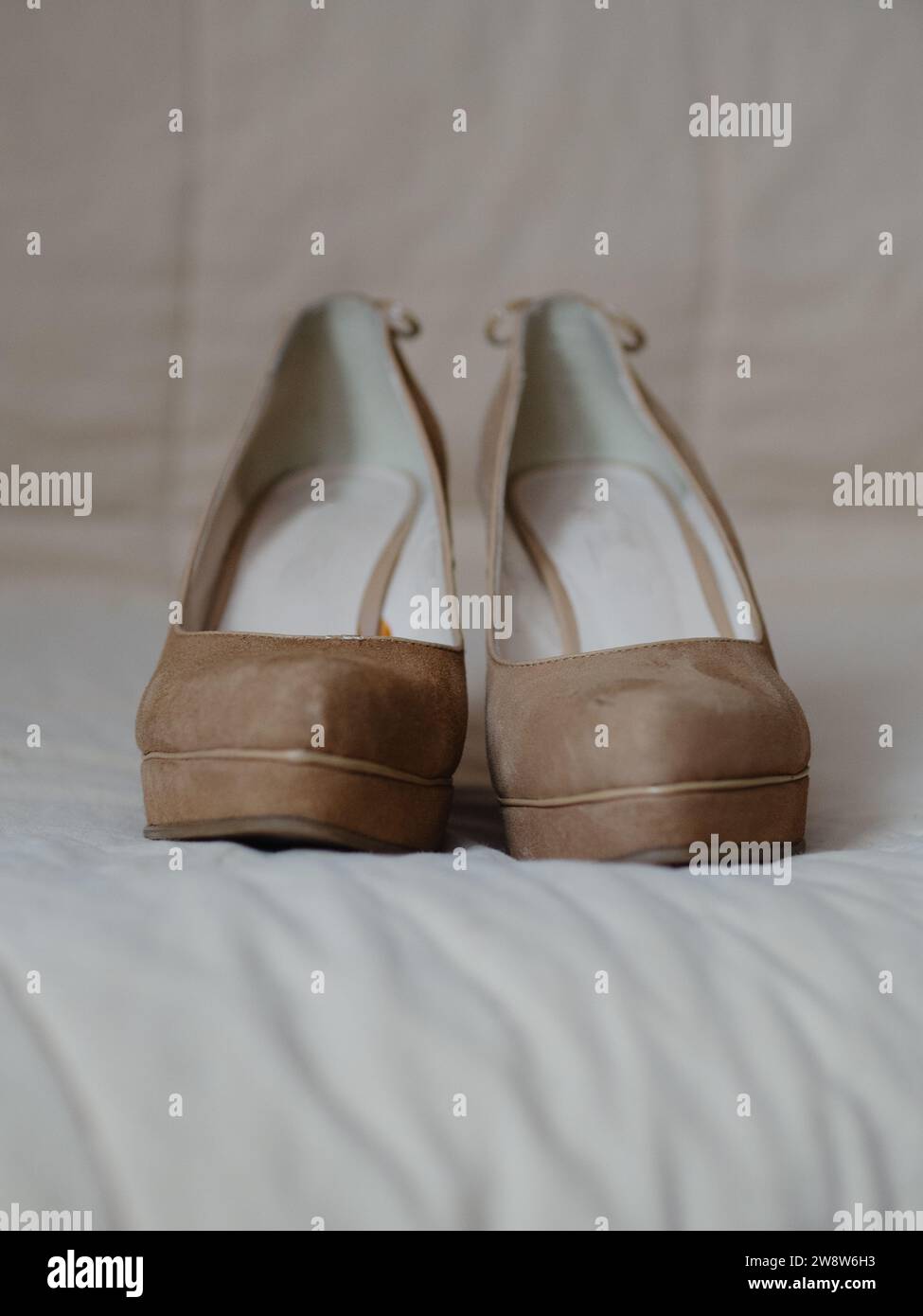 Vertikale Nahaufnahme von beigefarbenen Damenschuhen auf einer soliden, hohen Plattform aus echtem Leder (Wildleder). Auf der Rückseite mit Spitzenschleifen verziert. Vie Stockfoto