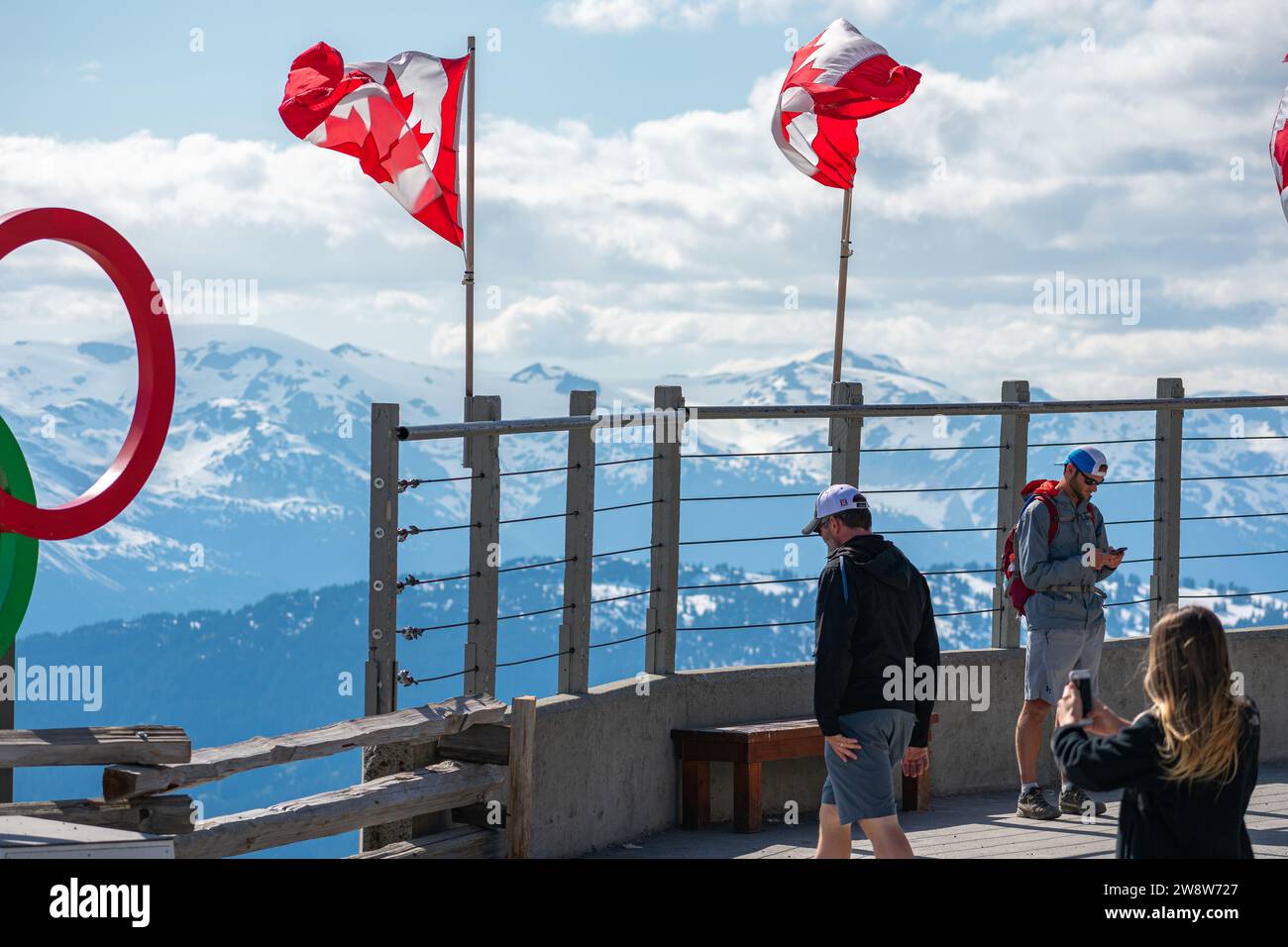 Besucher des Whistler Mountain bestaunen die raue Schönheit der Kanadischen Rocky Mountains, deren Nationalflagge Kanadas reiches Naturerbe symbolisiert. Stockfoto