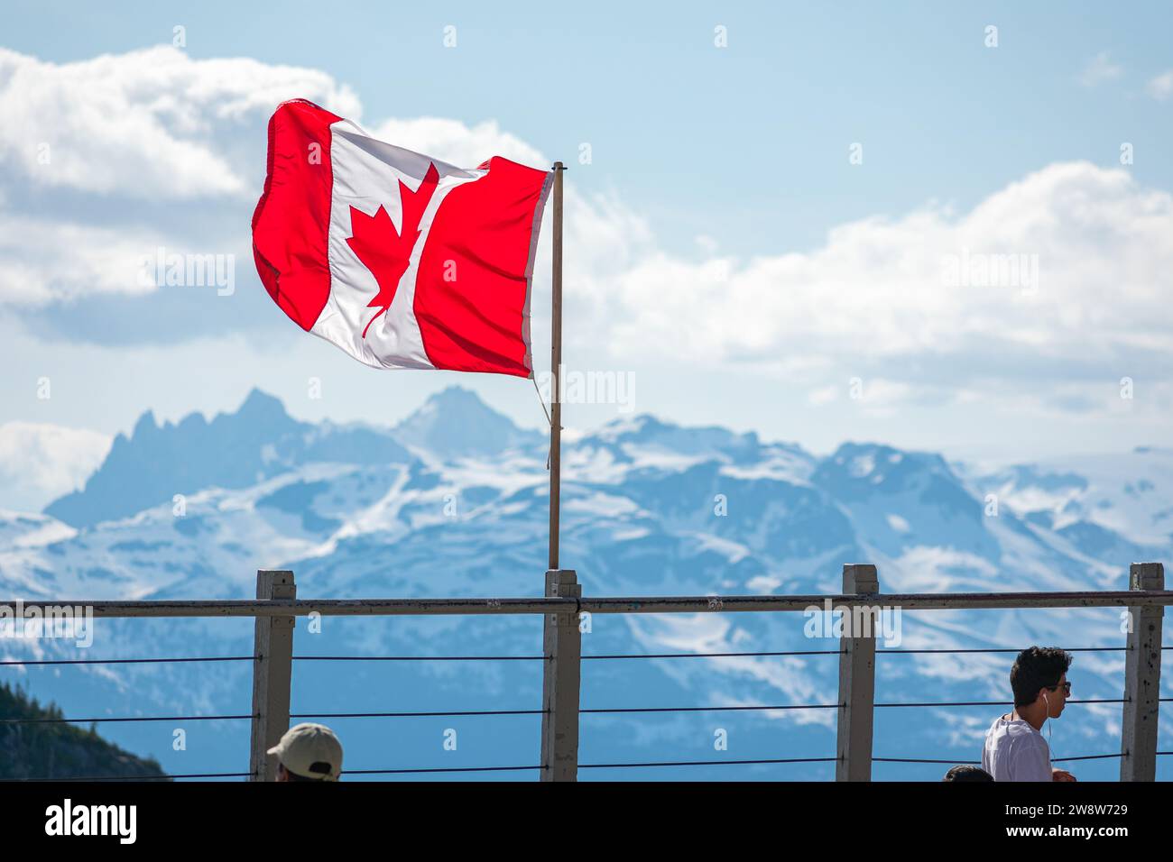 Die kanadische Flagge flattert stolz vor dem Hintergrund der schneebedeckten Gipfel des Whistler Mountain und symbolisiert den Geist des Abenteuers in British Columbia. Stockfoto