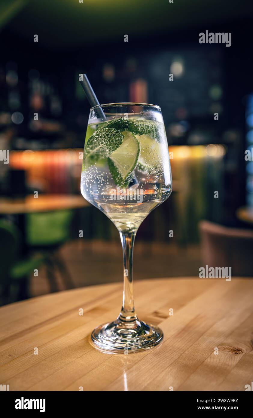 Glas Gin Tonic mit Limette serviert im Becher mit Trinkstroh Stockfoto