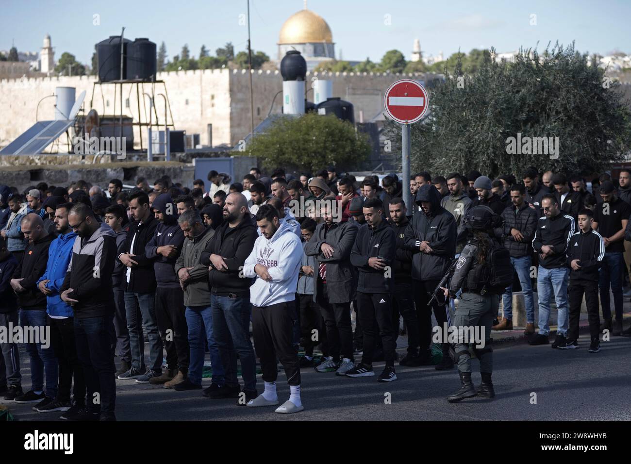 Palestinian Muslim worshipers who were prevented from entering the Al-Aqsa Mosque pray outside Jerusalem's Old City as Israeli forces stand guard Friday Dec. 22, 2023. (AP Photo/Mahmoud Illean) Stockfoto