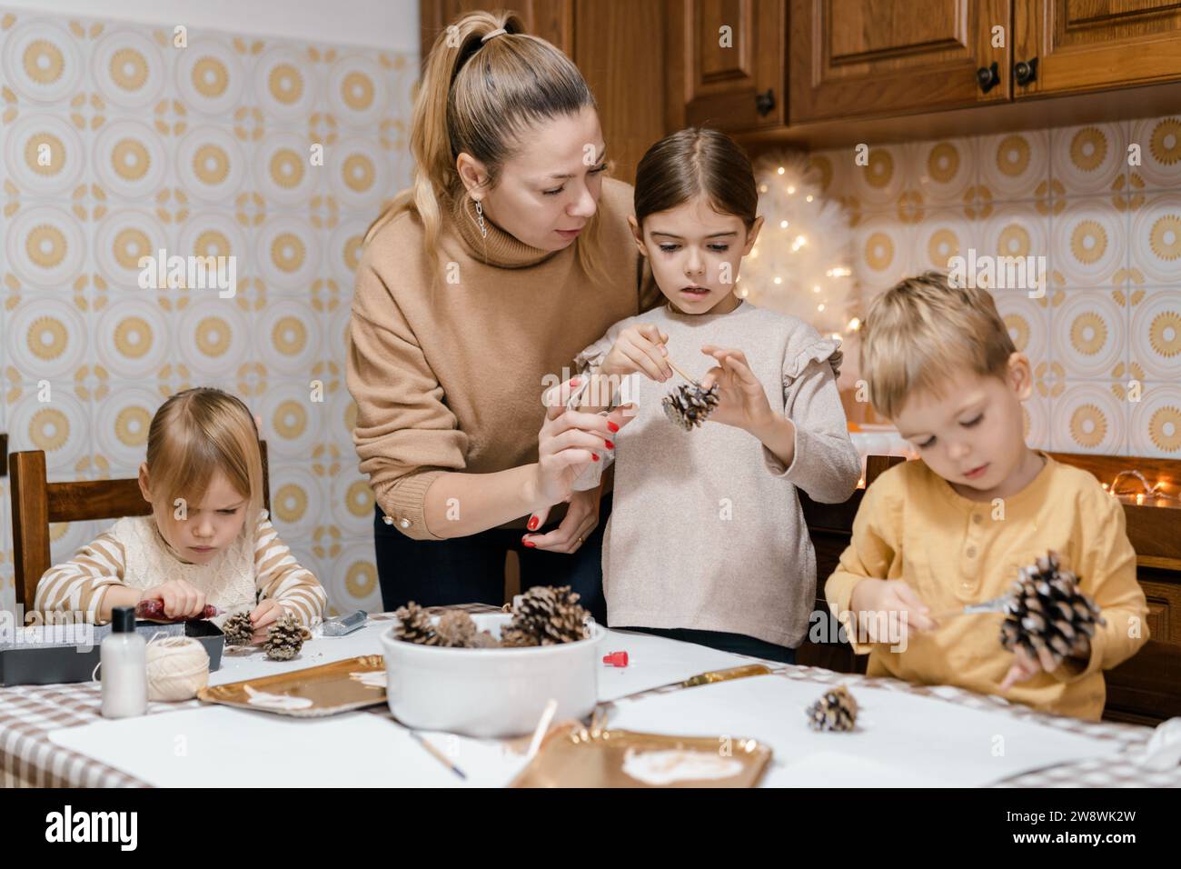 Mama und Kinder machen weihnachtsbasteln aus Tannenzapfen Stockfoto
