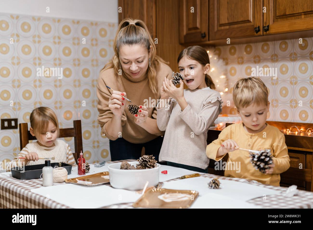 Mama und Kinder machen weihnachtsbasteln aus Tannenzapfen Stockfoto